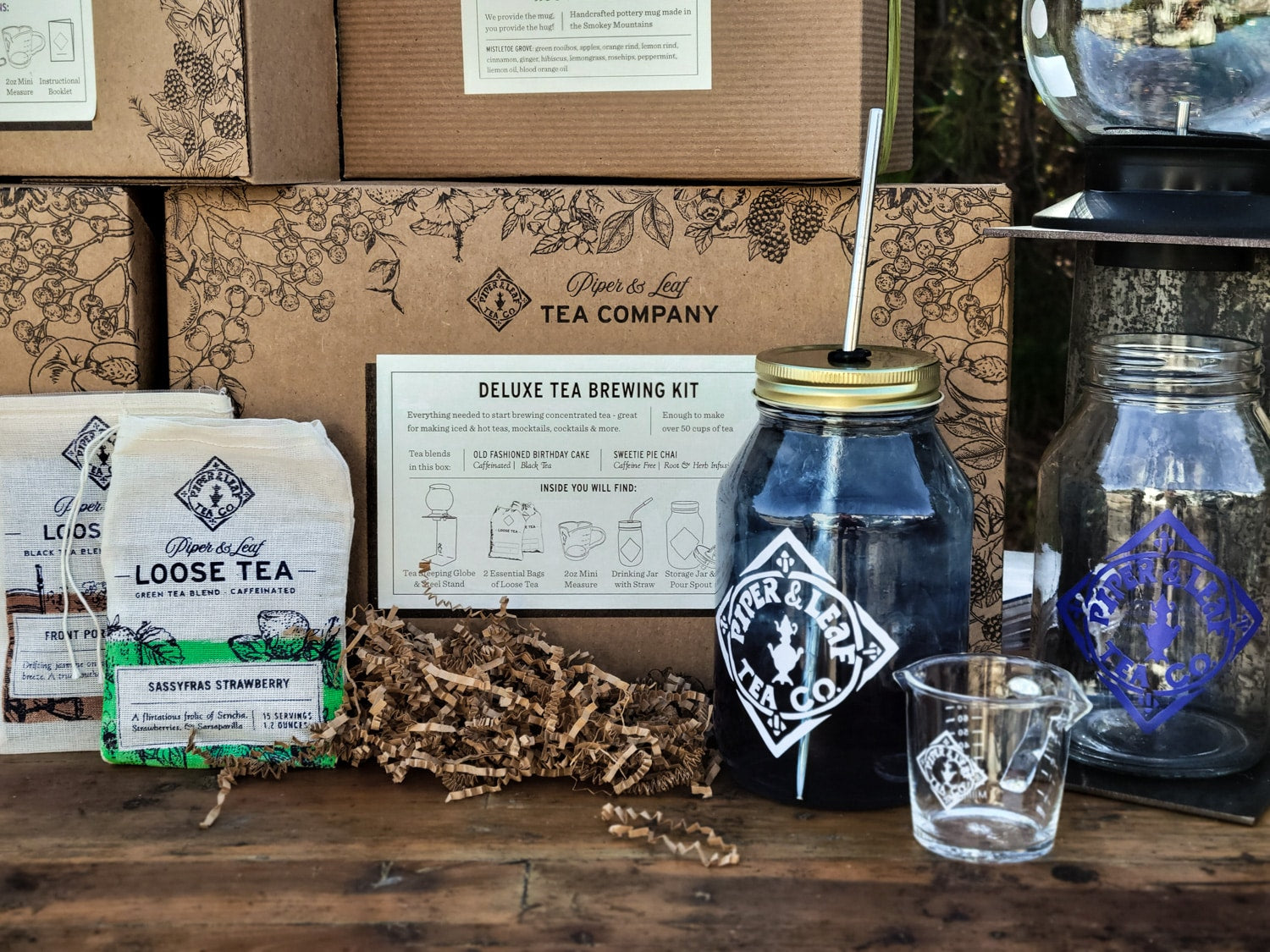 A Deluxe Piper Brew Kit from Piper & Leaf Tea Co. with tea and coffee on a wooden table.