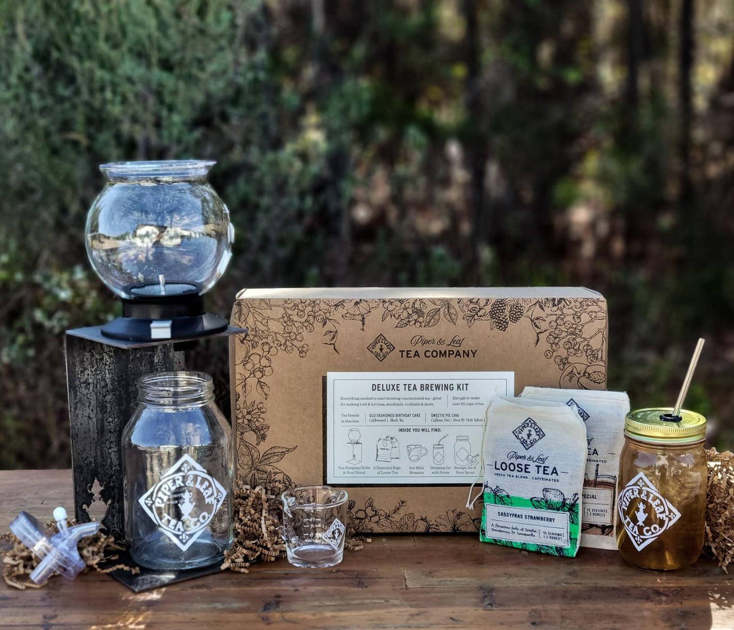 A Deluxe Piper Brew Kit from Piper & Leaf Tea Co. and a jar of honey on a wooden table with a hint of Concentrated Tea.