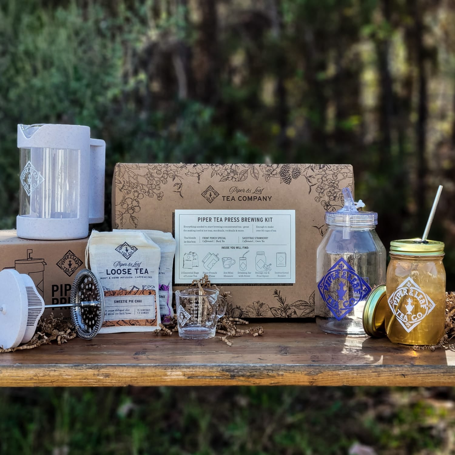 A box containing a jar of honey, a bottle of honey, and a Piper Press Brew Kit by Piper & Leaf Tea Co.
