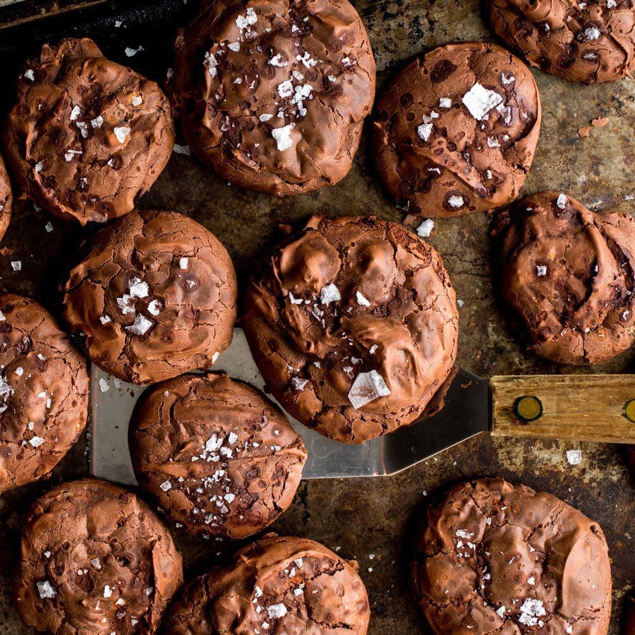 Freshly baked chocolate cookies being scooped off of the pan with a spatula