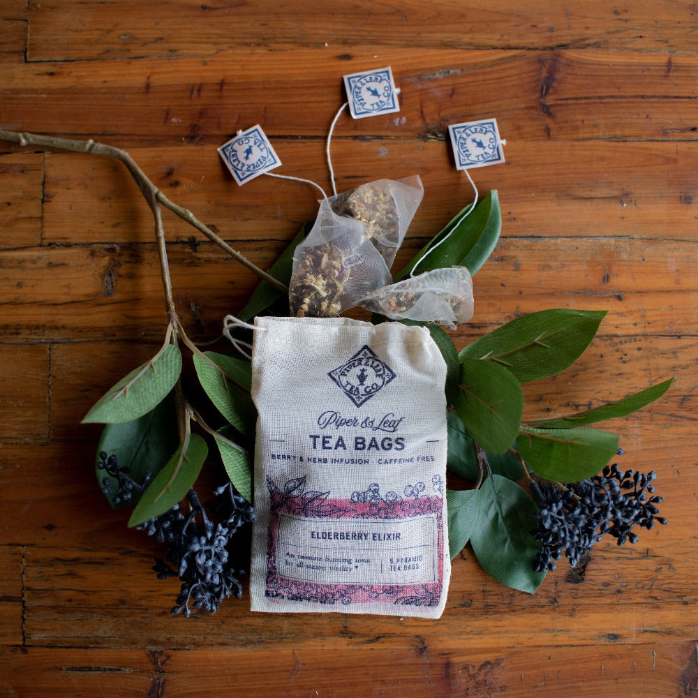 An Elderberry Elixir 9ct Tea Bag in Muslin, possibly infused with elderberries and echinacea, resting calmly on a rustic wooden table.