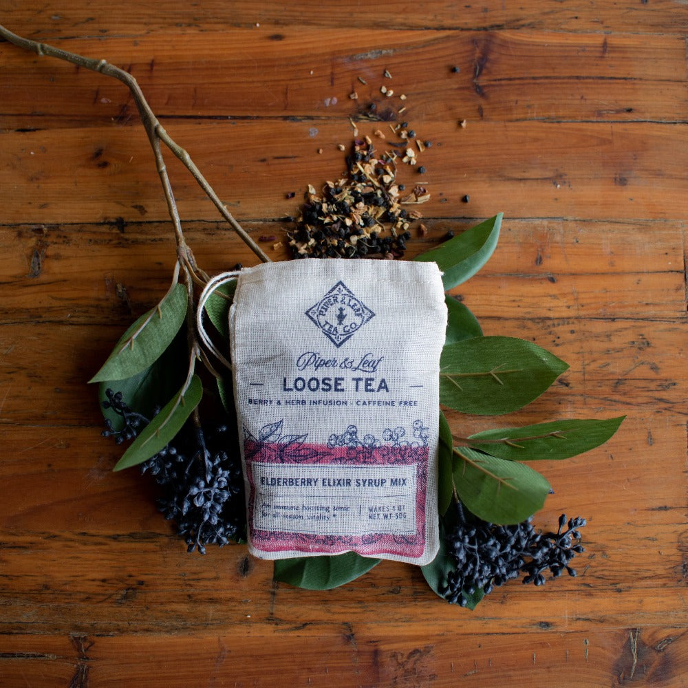 A bag of Piper & Leaf Tea Co.'s Elderberry Elixir Loose Leaf Tea - 15 Servings Tea on a wooden table, infused with immune-boosting elderberries and echinacea.