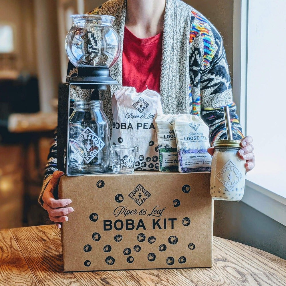 A woman holding a box with a Deluxe Boba Tea Kit from Piper & Leaf Tea Co. in it.