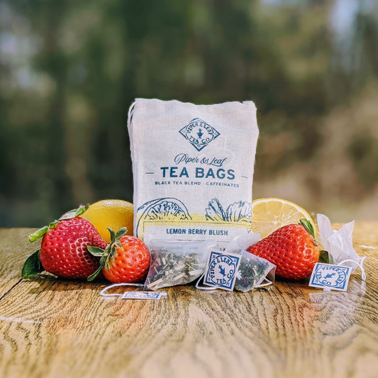 Refreshing Lemon Berry Blush 9ct Tea Bags in Muslin from Piper & Leaf Tea Co. with fruity flavors of strawberries and lemons on a wooden table.