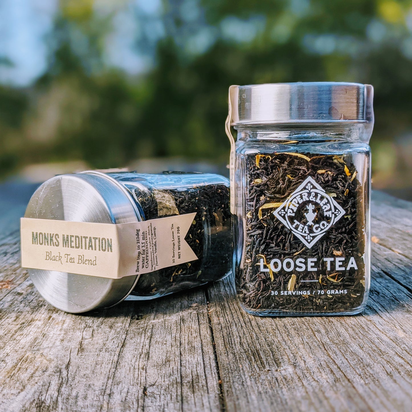 Two jars of Monks Meditation Glass Jar of Loose Leaf Tea - 30 Servings by Piper & Leaf Tea Co. placed on a wooden surface.