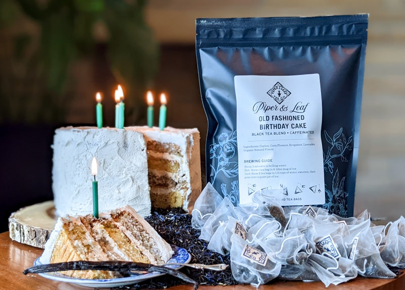 A Old Fashioned Birthday Cake Bulk Sachets - 70ct Tea Bags with candles on a table next to a bag of lavender. (Brand Name: Piper & Leaf Tea Co.)