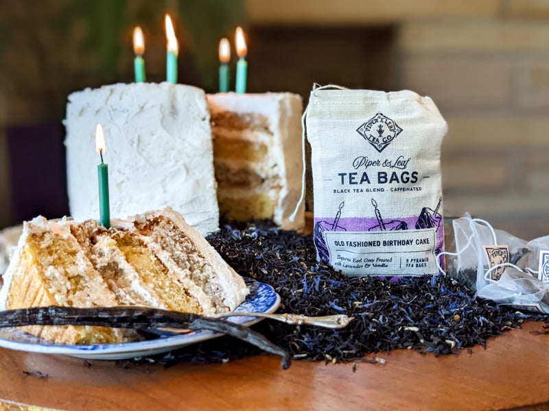 A lavender-infused Old Fashioned Birthday Cake 9ct Tea Bags in Muslin with candles on a plate. (Brand: Piper & Leaf Tea Co.)