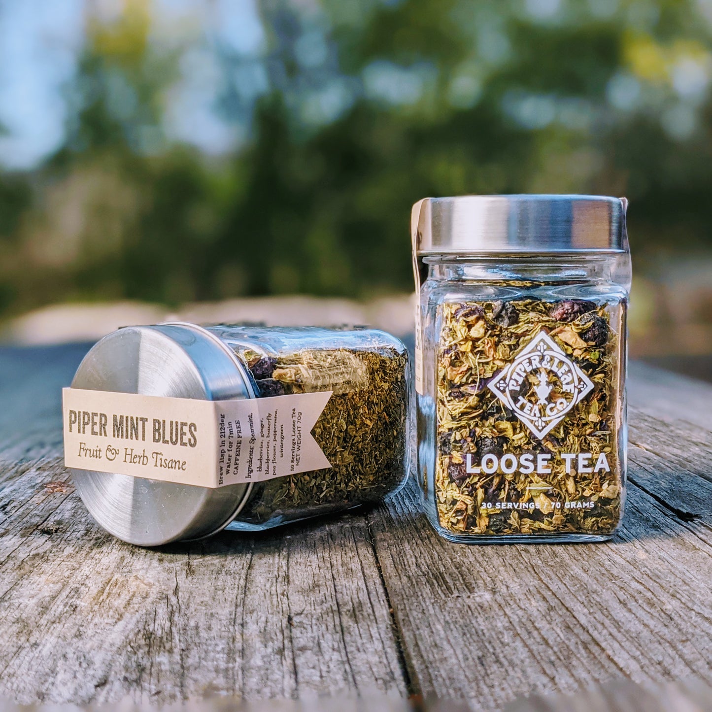 Piper & Leaf Tea Co.'s Piper Mint Blues Glass Jar of Loose Leaf Tea - 30 Servings with a hint of ginger on a wooden table.