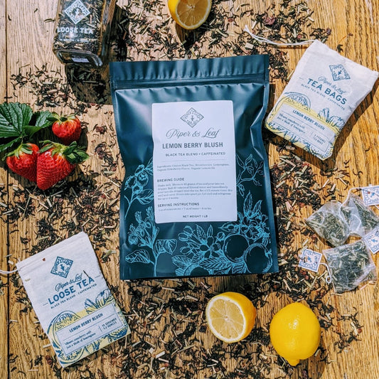 A bag of Piper & Leaf Tea Co. Lemon Berry Blush Bulk Sachets - 70ct Tea Bags with lemons and strawberries on a wooden table.