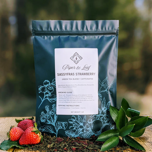 A Sassyfras Strawberry Pound Bag - 190 serving from Piper & Leaf Tea Co. alongside fresh strawberries on a wooden table.
