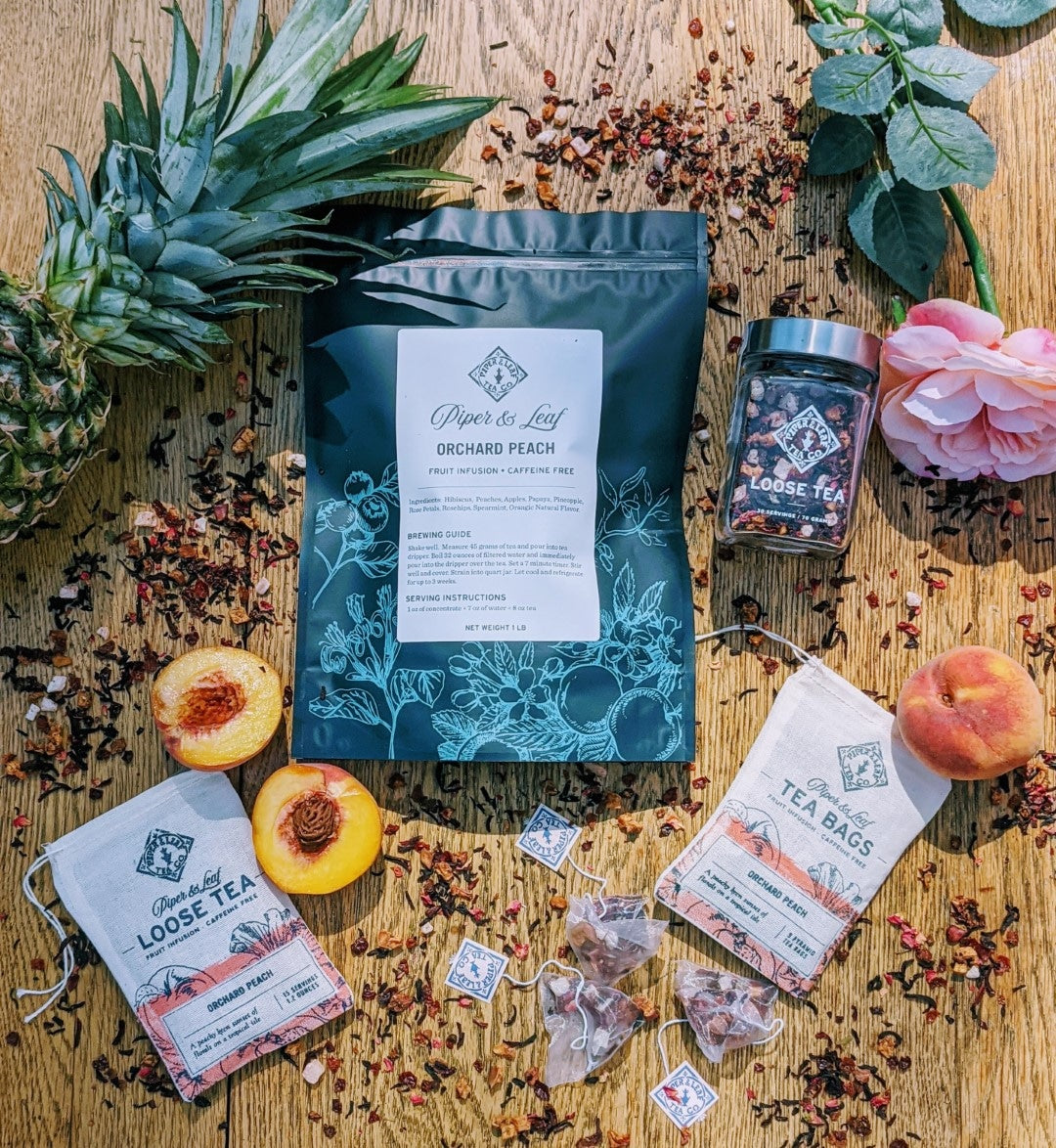 A vibrant pineapple and a Piper & Leaf Tea Co. Orchard Peach Pound Bag - 190 servings on a wooden table.