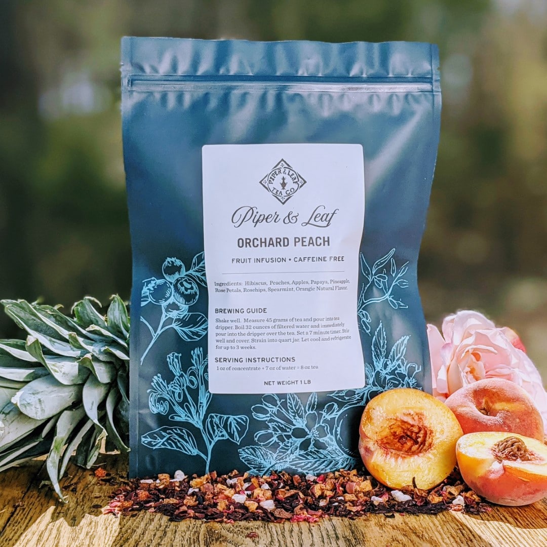 A vibrant Orchard Peach Pound Bag of Piper & Leaf Tea Co. on a wooden table.