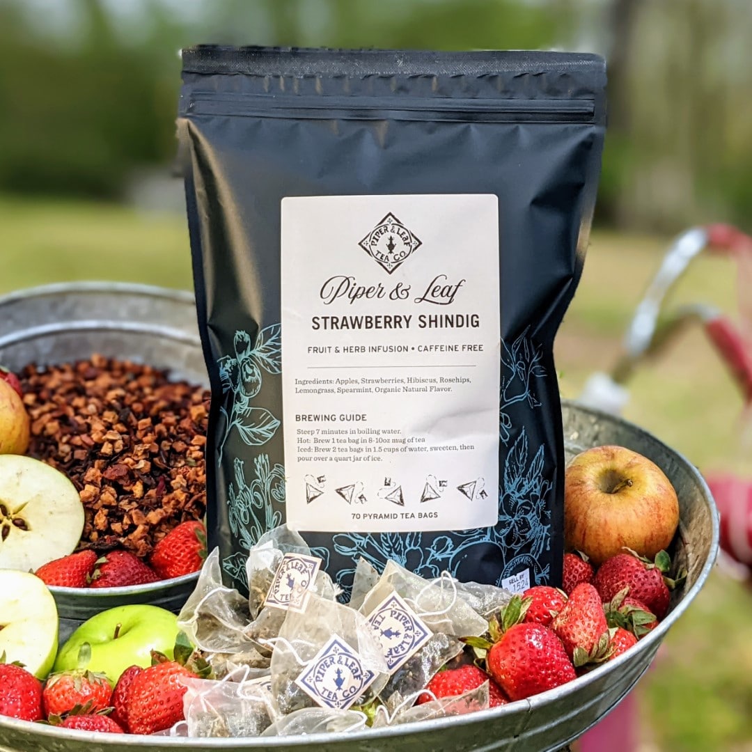 A basket full of fruit and a bag of Piper & Leaf Tea Co.'s Strawberry Shindig Bulk Sachets - 70ct Tea Bags.
