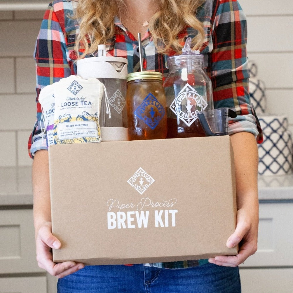 A woman holding a box with a Piper Press Brew Kit containing concentrated tea from Piper & Leaf Tea Co.