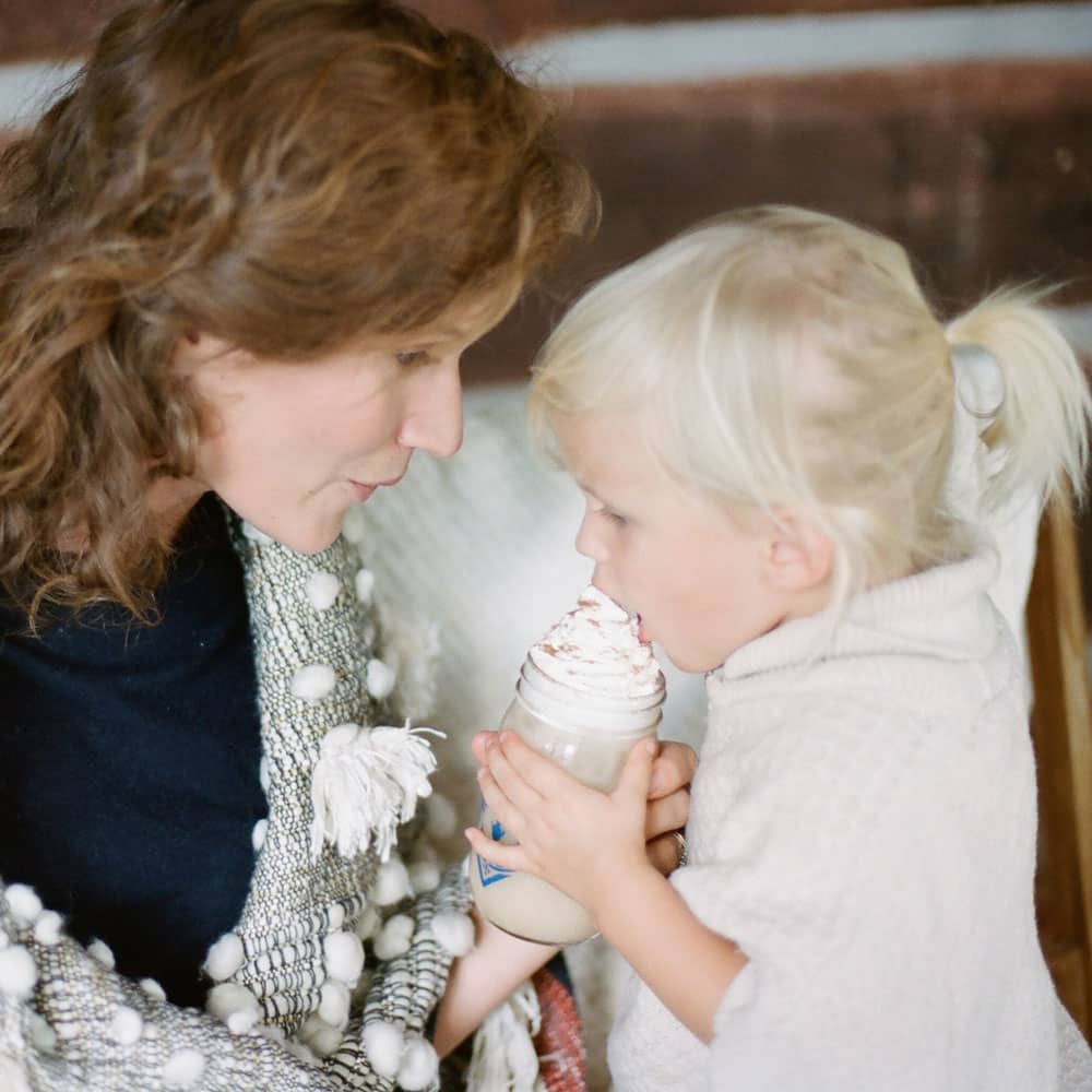 A little girl enjoys a whipped-cream-topped Sweetie Pie Chai milk tea with her mother