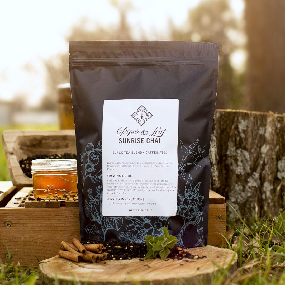 A Sunrise Chai Pound Bag from Piper & Leaf Tea Co. sitting on a spiced wooden table.