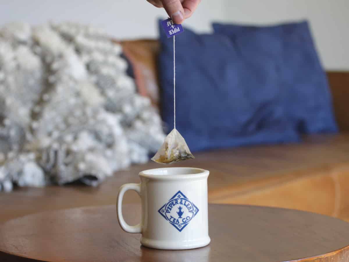 A tea bag being pulled out of a Piper & Leaf mug