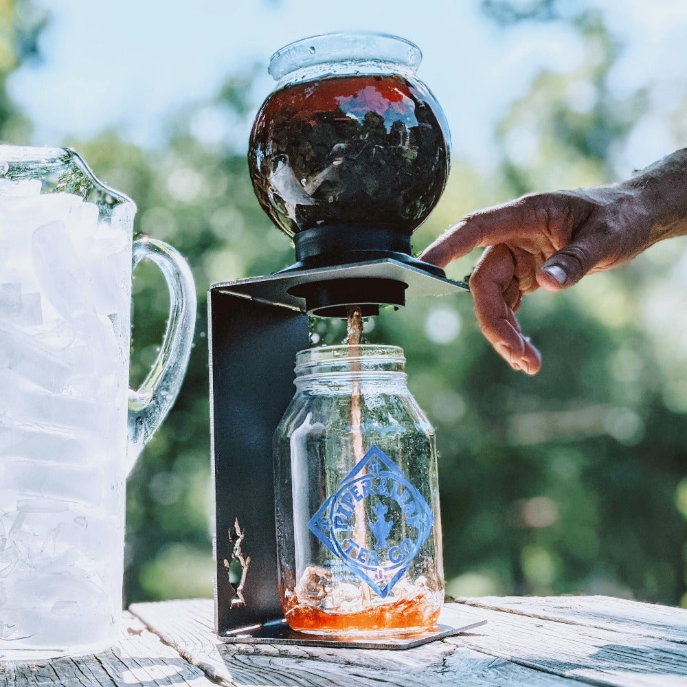 A person brewing iced tea with the Deluxe Piper Brew Kit, pouring the Concentrated Tea into a mason jar.