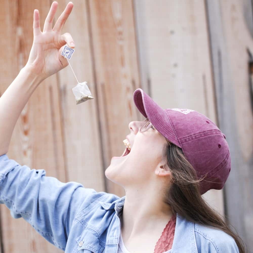 A girl playfully lowers a sachet tea bag toward her mouth