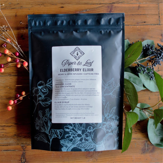 A bag of Piper & Leaf Tea Co.'s Elderberry Elixir Pound Bag- 190 servings, an echinacea-infused coffee with immune-boosting properties, placed on a rustic wooden table.
