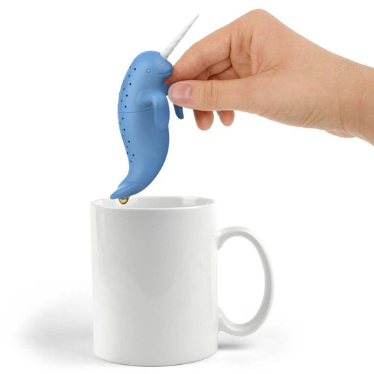 A narwhal shaped Fred-brand tea strainer over a mug: Spiked Tea