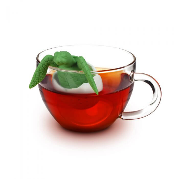 A sea turtle shaped Fred-brand tea strainer in a glass tea cup: the Tea Turtle